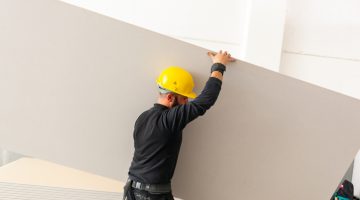 Worker at work in the construction of a plasterboard wall.