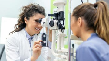 Eye doctor with female patient during an examination in modern clinic. Ophthalmologist is using special medical equipment for eye health saving and improving.