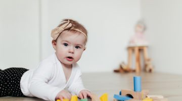 Little kid playing with colorful wooden building blocks. Blurred background. High quality photo