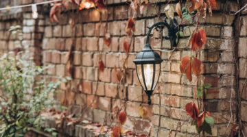 Vintage brick wall covered with autumn leaves and a lantern hanging at it at the autumn yard. Seasons concept. Stock photo