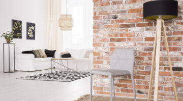 Grey designer chair and black lamp by the red brick wall