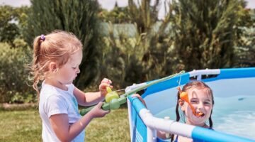 Children playing in a pool with fishing rod toy in a home garden. Kids having fun playing together on a summer sunny day