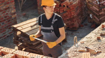 Holding plan in hands. Construction worker in uniform and safety equipment have job on building.
