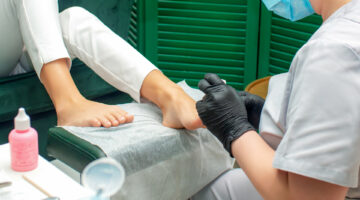 Woman receiving pedicure procedure on feet in spa salon.