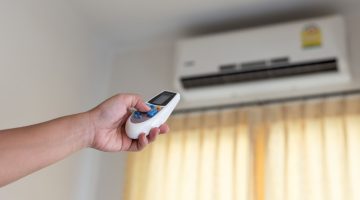 hand with remote control directed on the conditioner