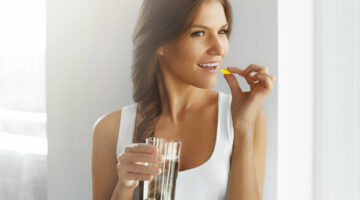 Diet. Nutrition. Vitamins. Healthy Eating, Lifestyle. Close Up Of Happy Smiling Woman Taking Pill With Cod Liver Oil Omega-3 And Holding A Glass Of Fresh Water In Morning. Vitamin D, E, A Fish Oil Capsules.